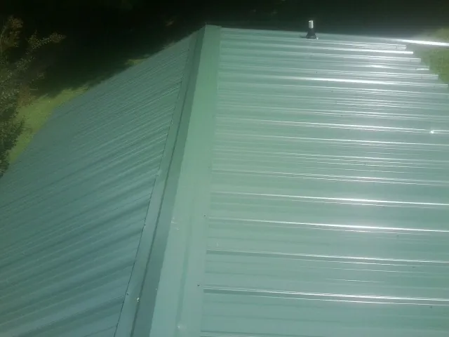 New green metal panels meeting at the ridge of a roof — Flat Roof Repair work by our crew in Grand Junction