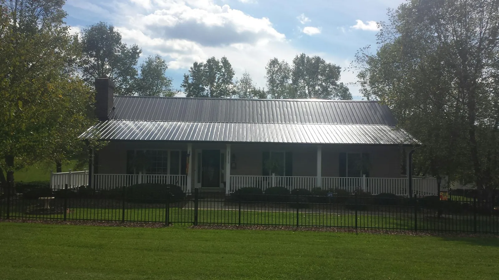 Gray metal roof on a brick ranch with a full width front porch — Gutter Guard Installation work by our crew in Grand Junction
